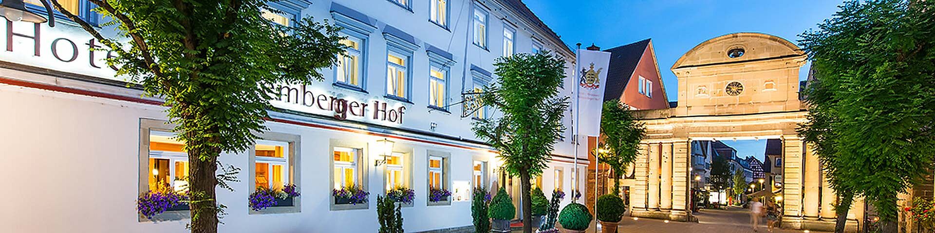 [Translate to Englisch:] Ein Hotel in Öhringen ist zu sehen, daneben das beleuchtete "Obere Tor" aus Sandstein.